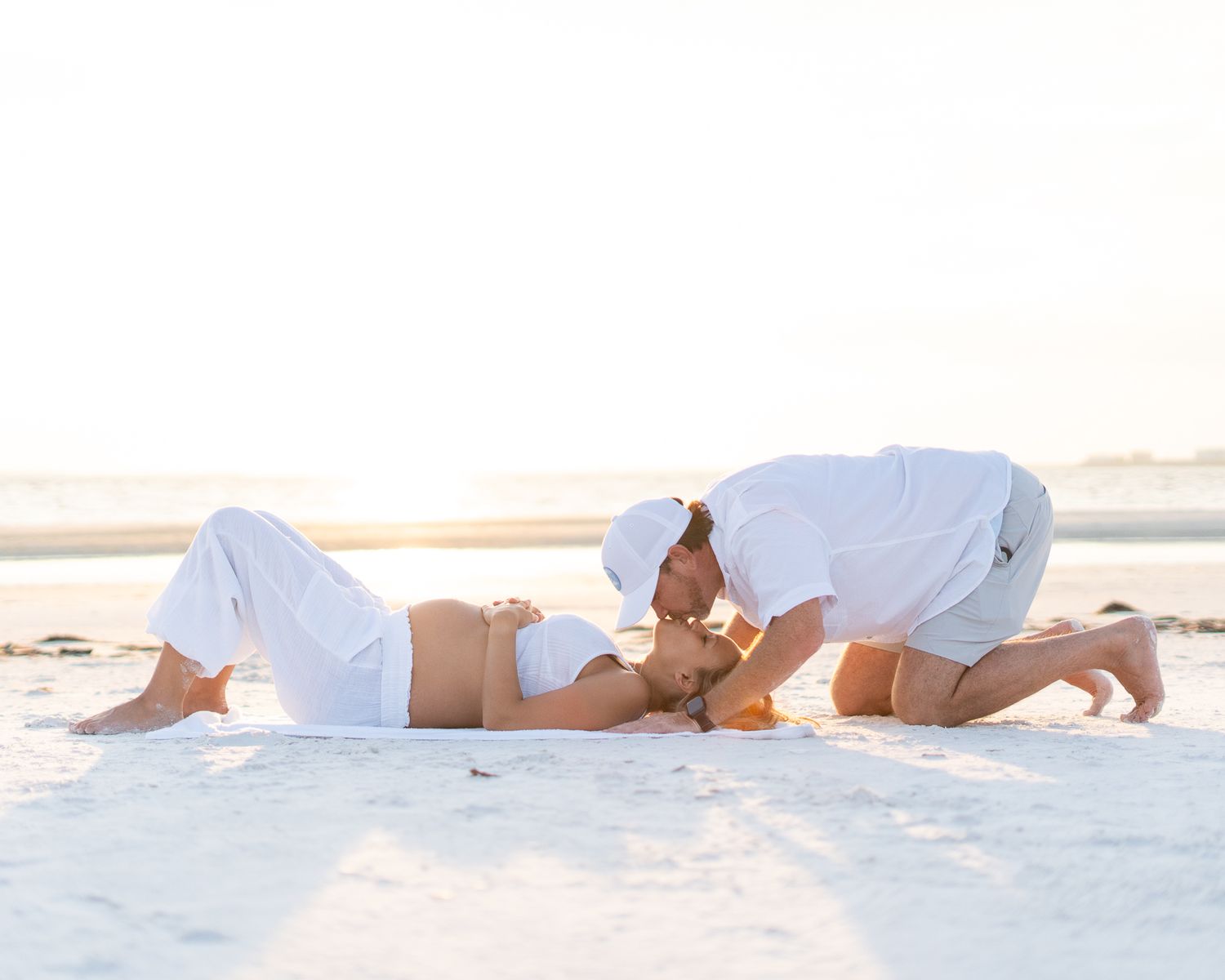 White-clad figures recline on a pristine sandy beach at sunset.