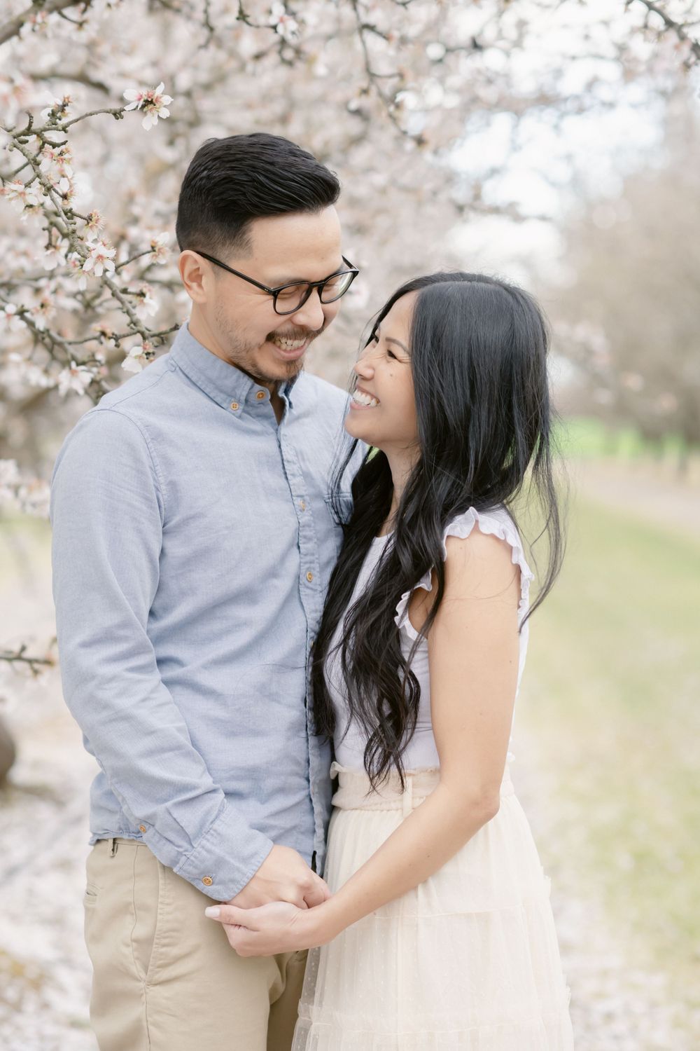 A loving couple shares a joyful moment under blooming cherry blossom trees.
