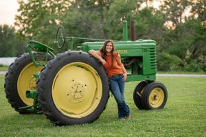 Vintage green John Deere tractor displayed on a grassy lawn at golden hour.
