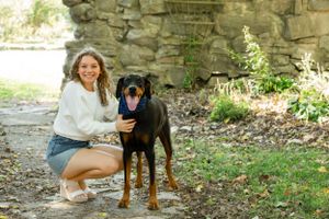 Happy moment with a black and tan dog on a stone path surrounded by greenery.