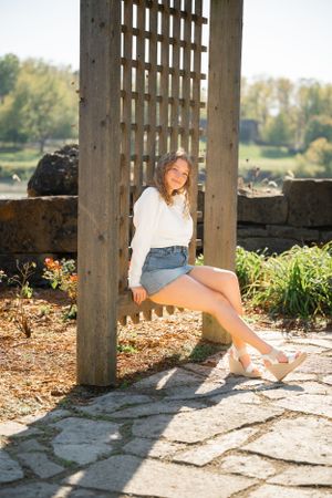 Casual outdoor photo against a wooden lattice structure with sunlit garden in background.