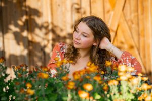 Dreamy garden portrait surrounded by orange and yellow flowers in soft lighting.