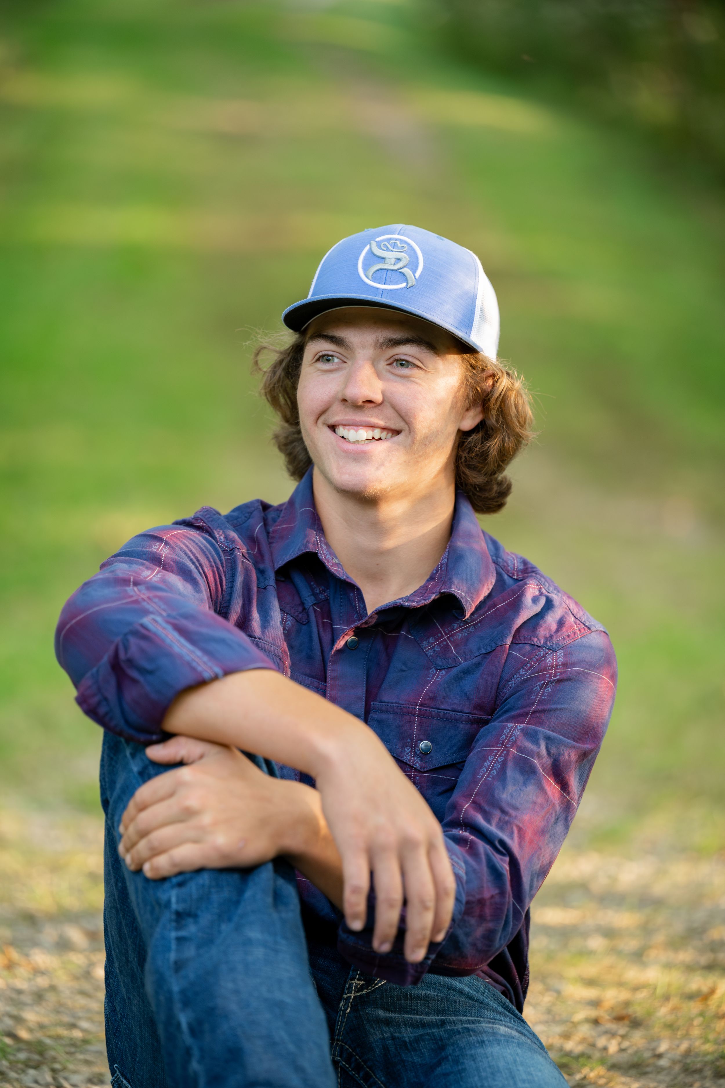 A casual outdoor portrait of someone wearing a baseball cap and plaid shirt.