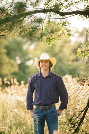 A western-styled portrait with cowboy hat and denim against golden sunset foliage.