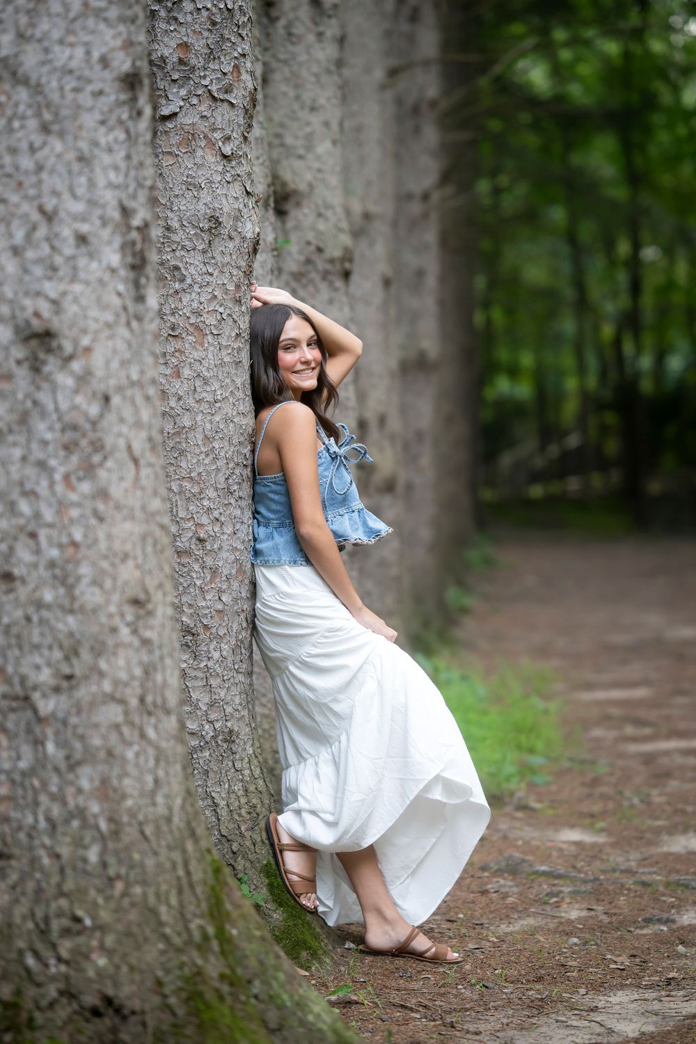Forest portrait session featuring a white dress against large tree trunks.