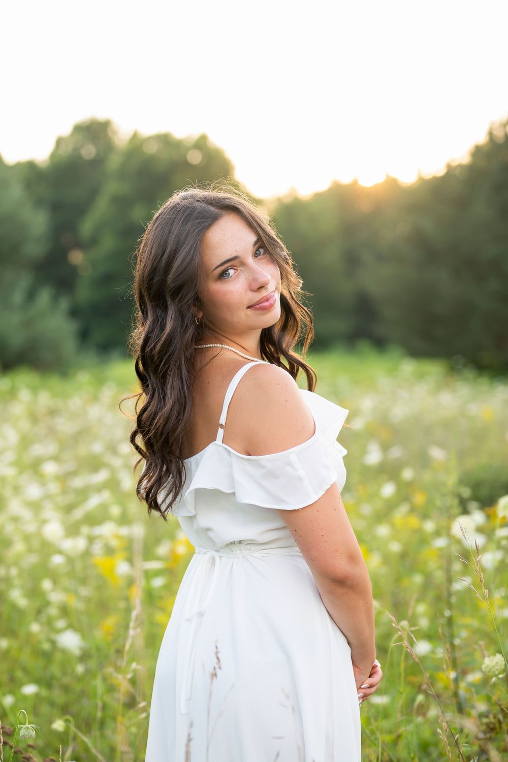 White sundress portrait in meadow with golden evening light filtering through.