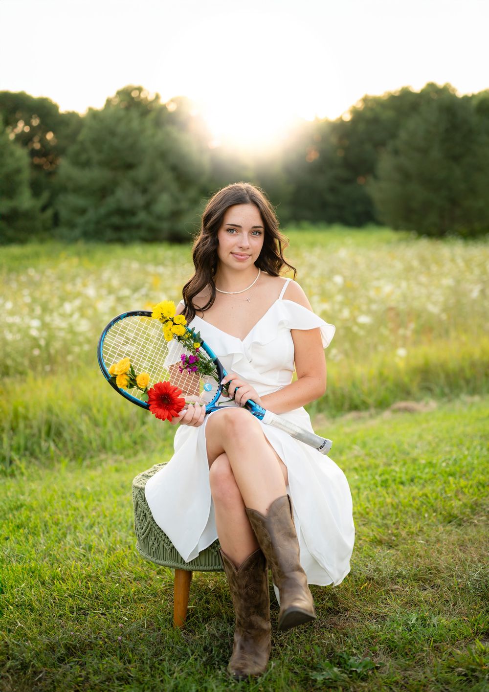 A summer portrait on a wooden chair with tennis racket and sunflowers at sunset.