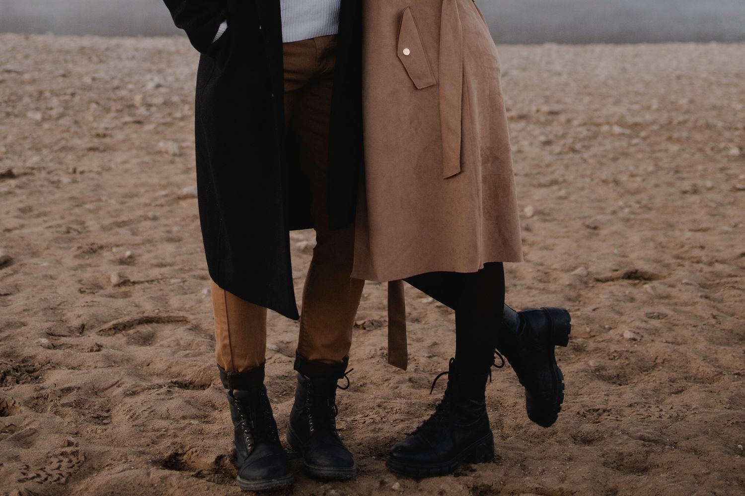 Detail shot of a couple's color coordinated, biege and black outfits.
