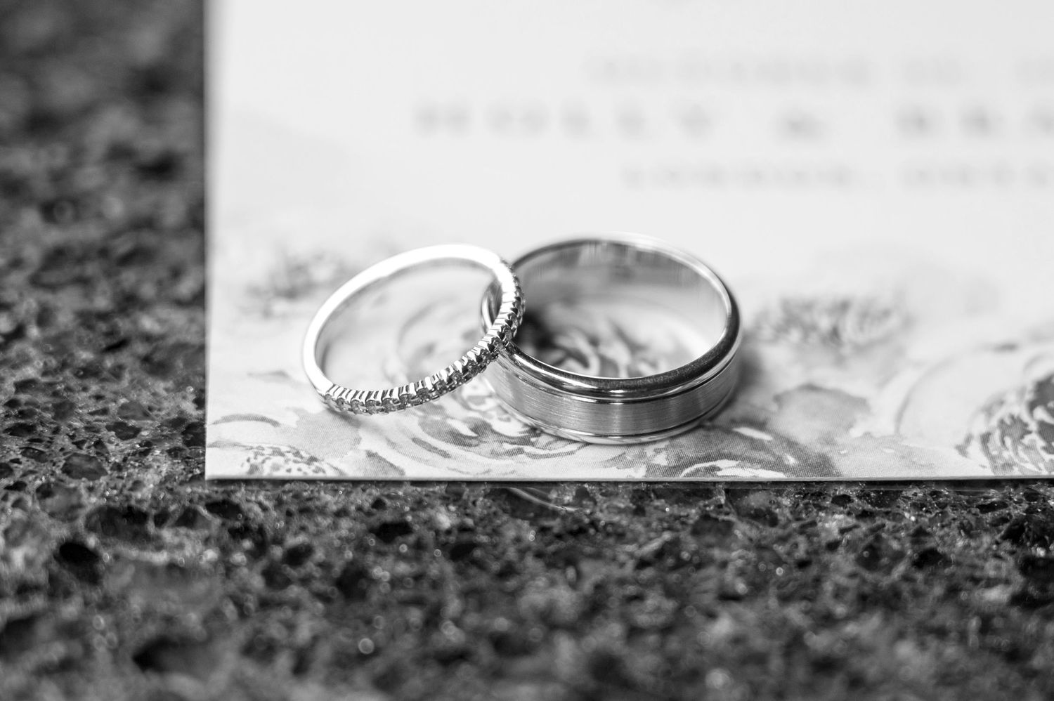 Close-up black and white capture of embrace showing delicate lace wedding dress details.