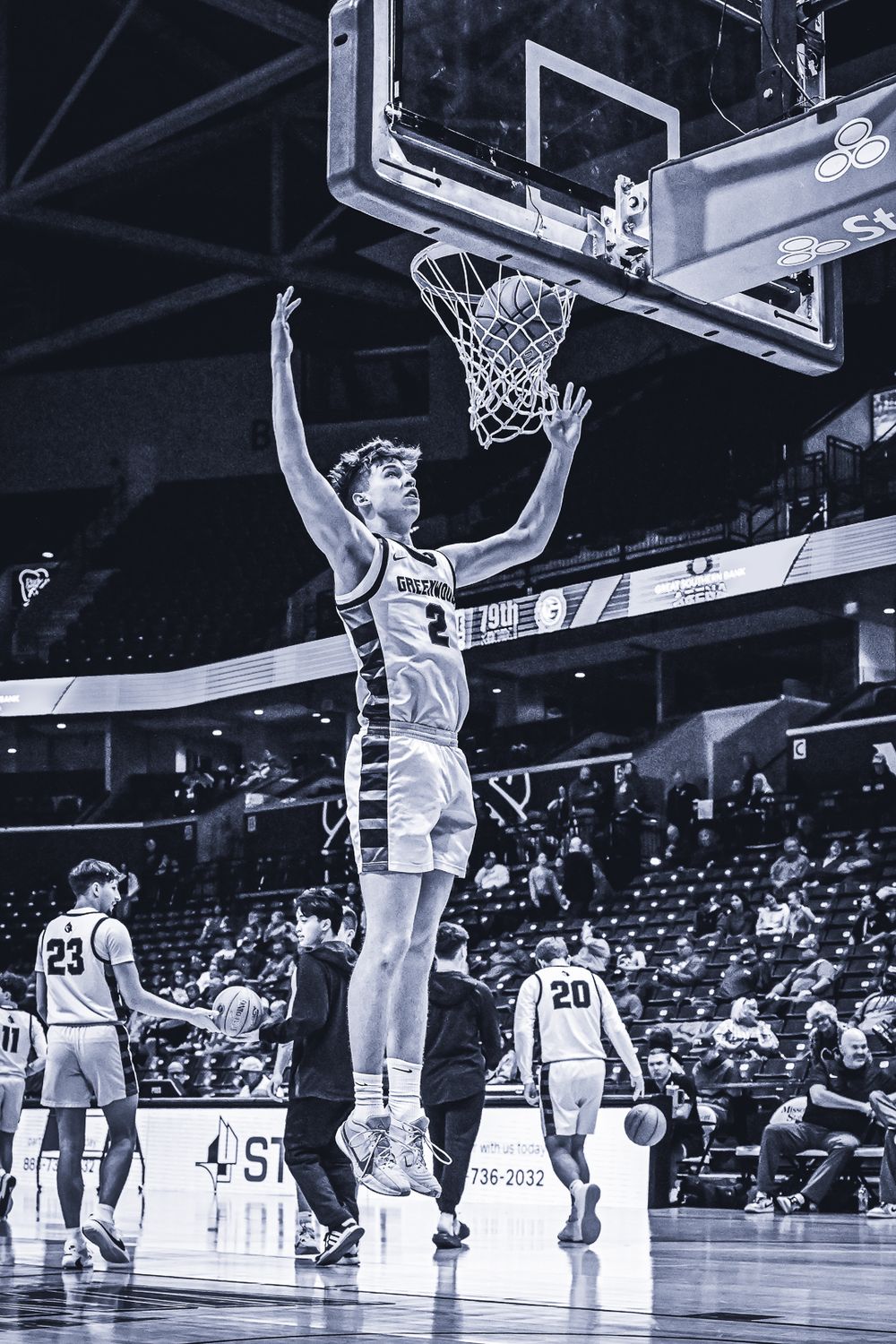 Player reaches up for a basketball rebound during a competitive indoor game.
