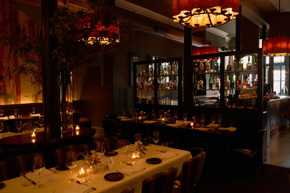 Intimate restaurant interior with warm lighting, dark wood tables and romantic ambiance.