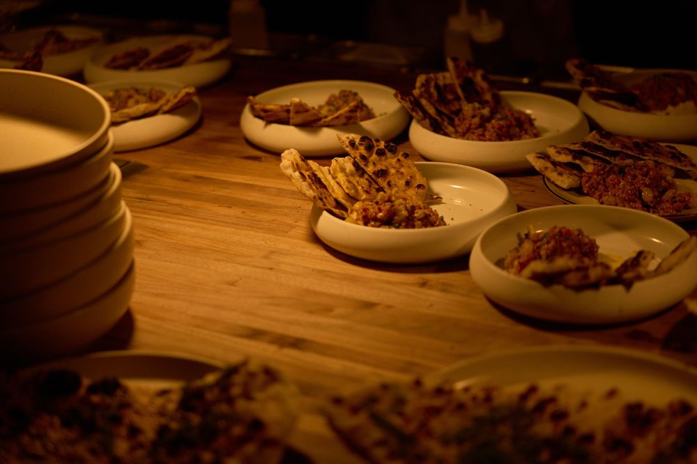 Small plates of food arranged on a wooden table in warm lighting.
