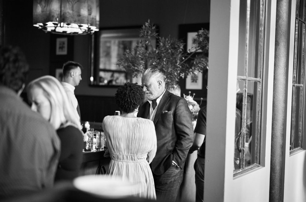Black and white photo of people gathered in an elegant dining room setting.