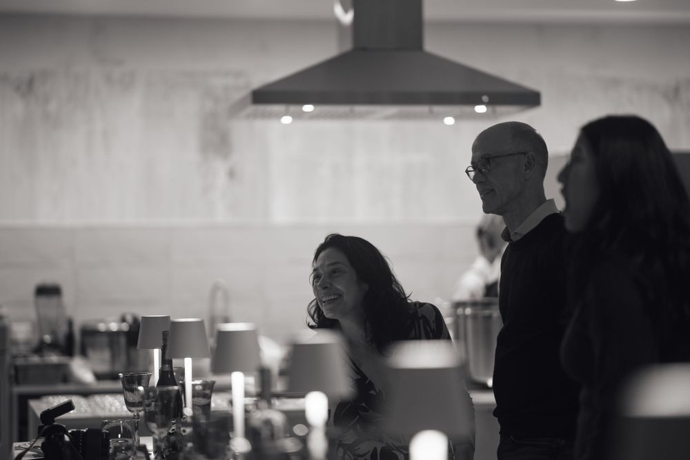 Black and white photo of guests mingling in a dimly lit kitchen space.