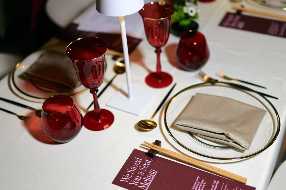 Elegant table setting with red wine glasses and menu on white tablecloth.
