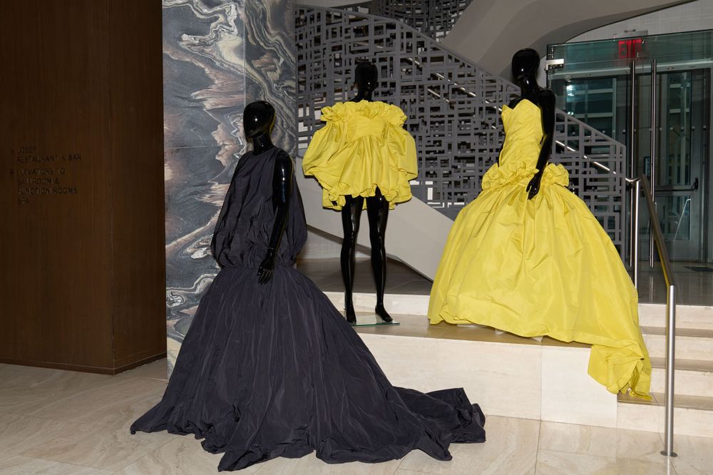 Display of dramatic black and bright yellow ball gowns in a modern gallery space.