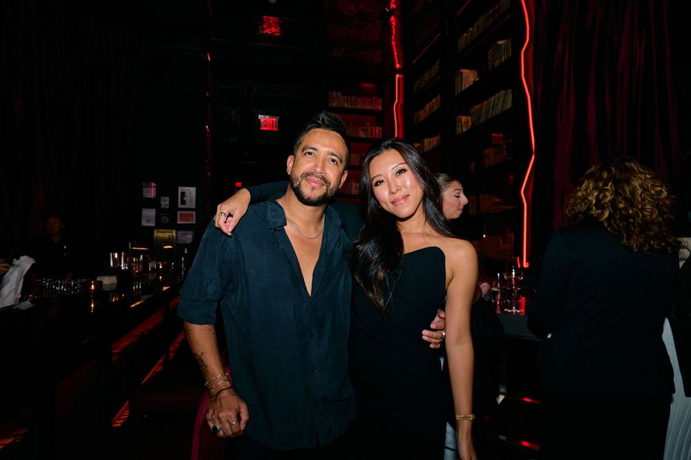 Friends poses together at an event with dark ambient lighting and red accents.