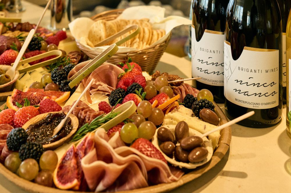 Charcuterie board with fresh berries, meats and wine bottles on display.