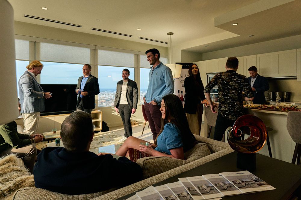 Group gathering in modern high-rise apartment with panoramic city views.