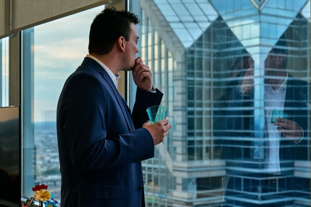 Business professional looking out office window at urban skyline.
