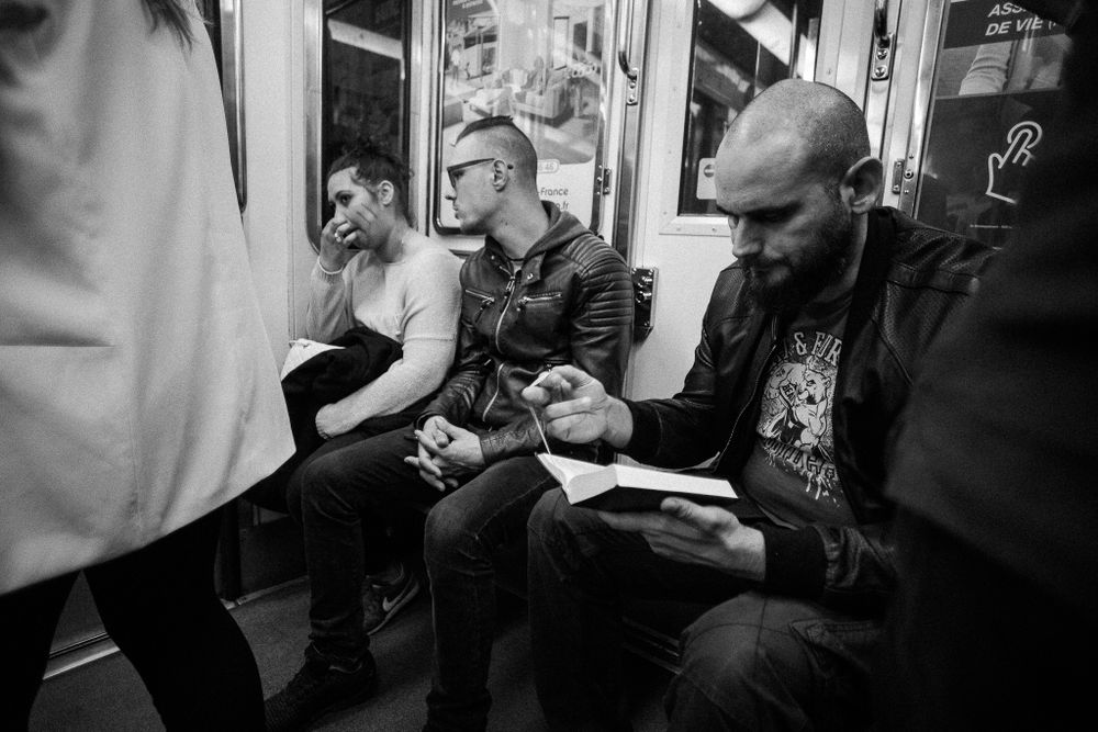 Commuters absorbed in their phones while riding public transit in black and white.