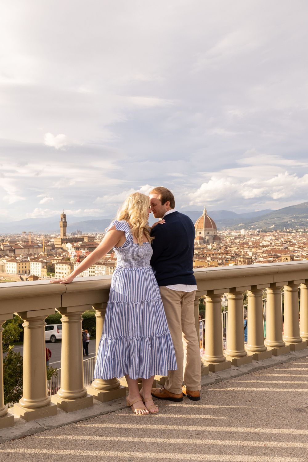 A couple enjoying the panoramic view of Florence from a balcony with classic Italian architecture.