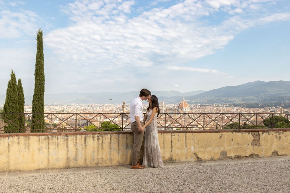 A romantic couple embraces while overlooking the cityscape of Florence from a scenic viewpoint.