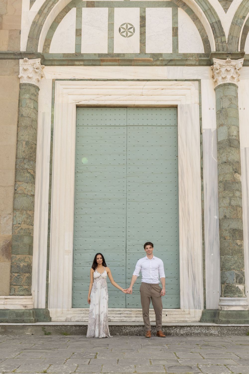 A couple poses in front of a grand architectural doorway with marble columns in Florence.