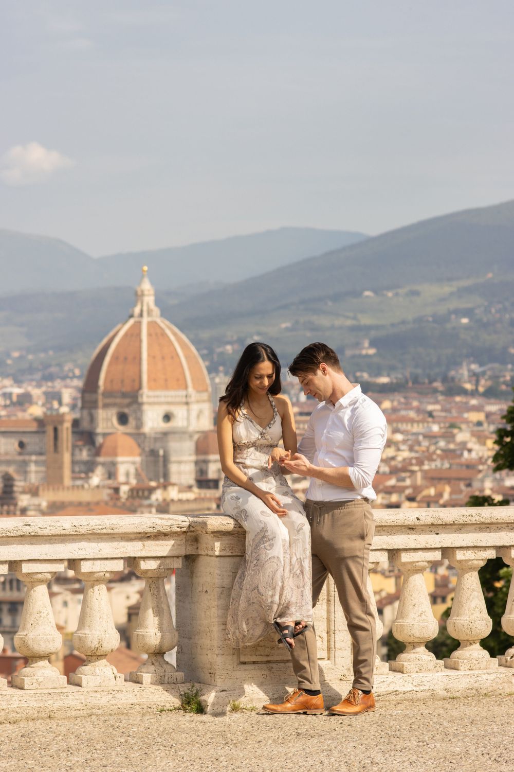 A couple shares a moment at Piazzale Michelangelo with Florence's Duomo cathedral in the background.