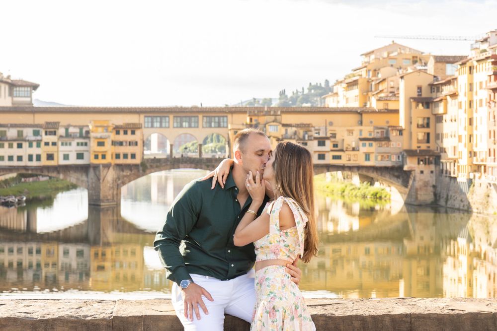 A romantic moment captured at the Ponte Vecchio bridge in Florence with golden evening light.