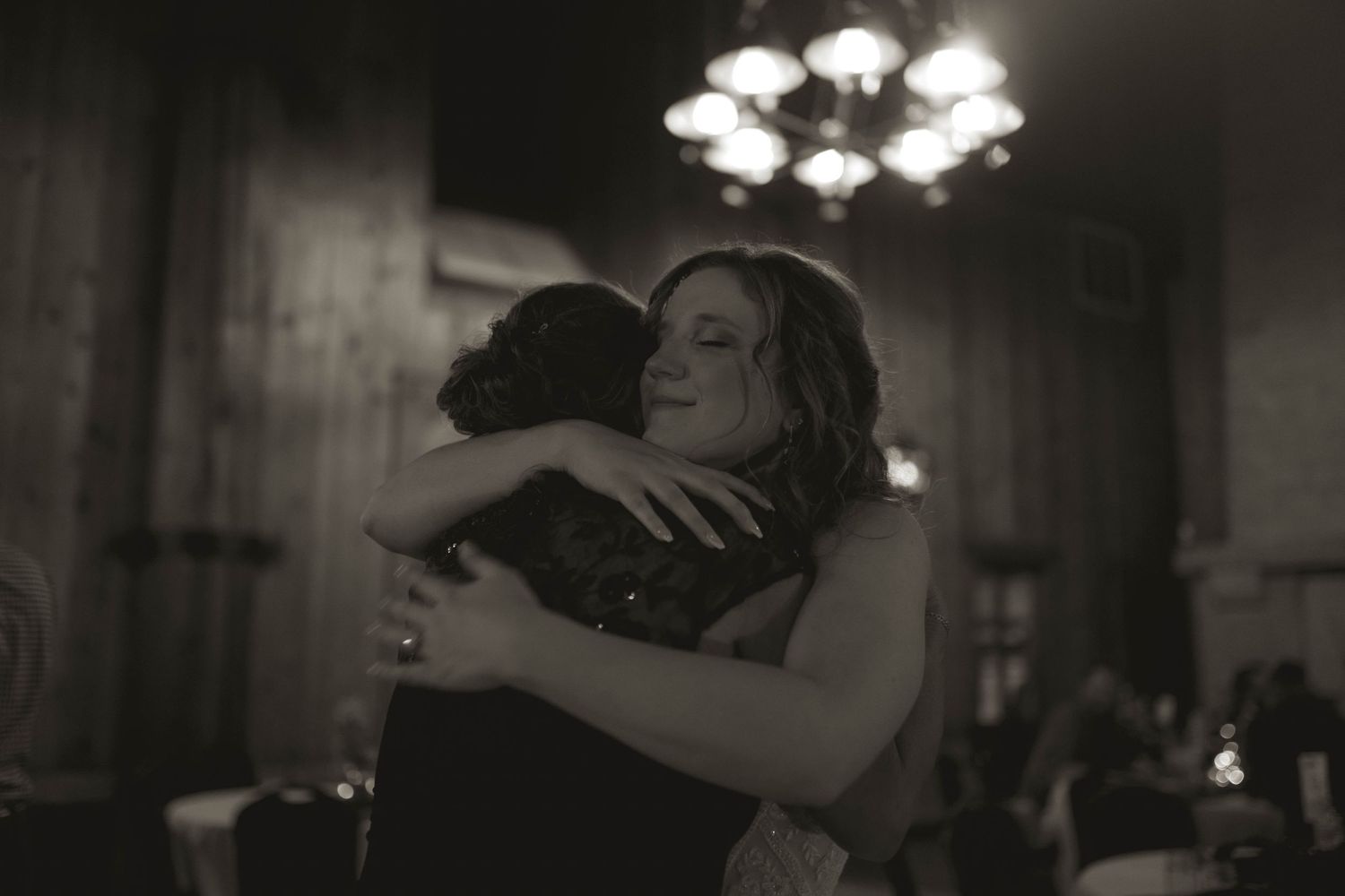 Couples dancing under elegant chandeliers in a dimly lit ballroom setting.