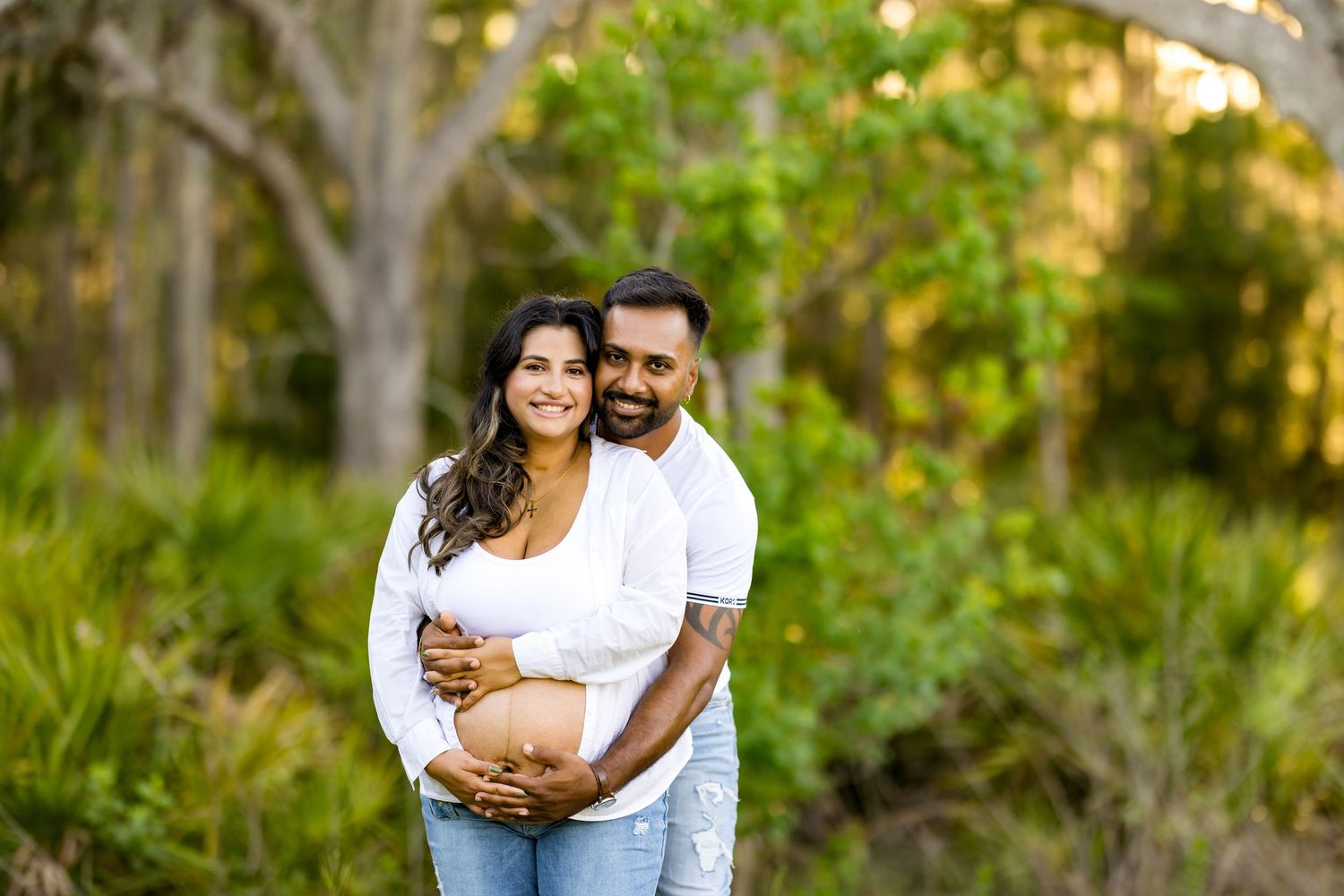 Romantic maternity photoshoot in nature with couple wearing coordinated white and denim outfits. Photos by Tampa Photographer DigitalMyst