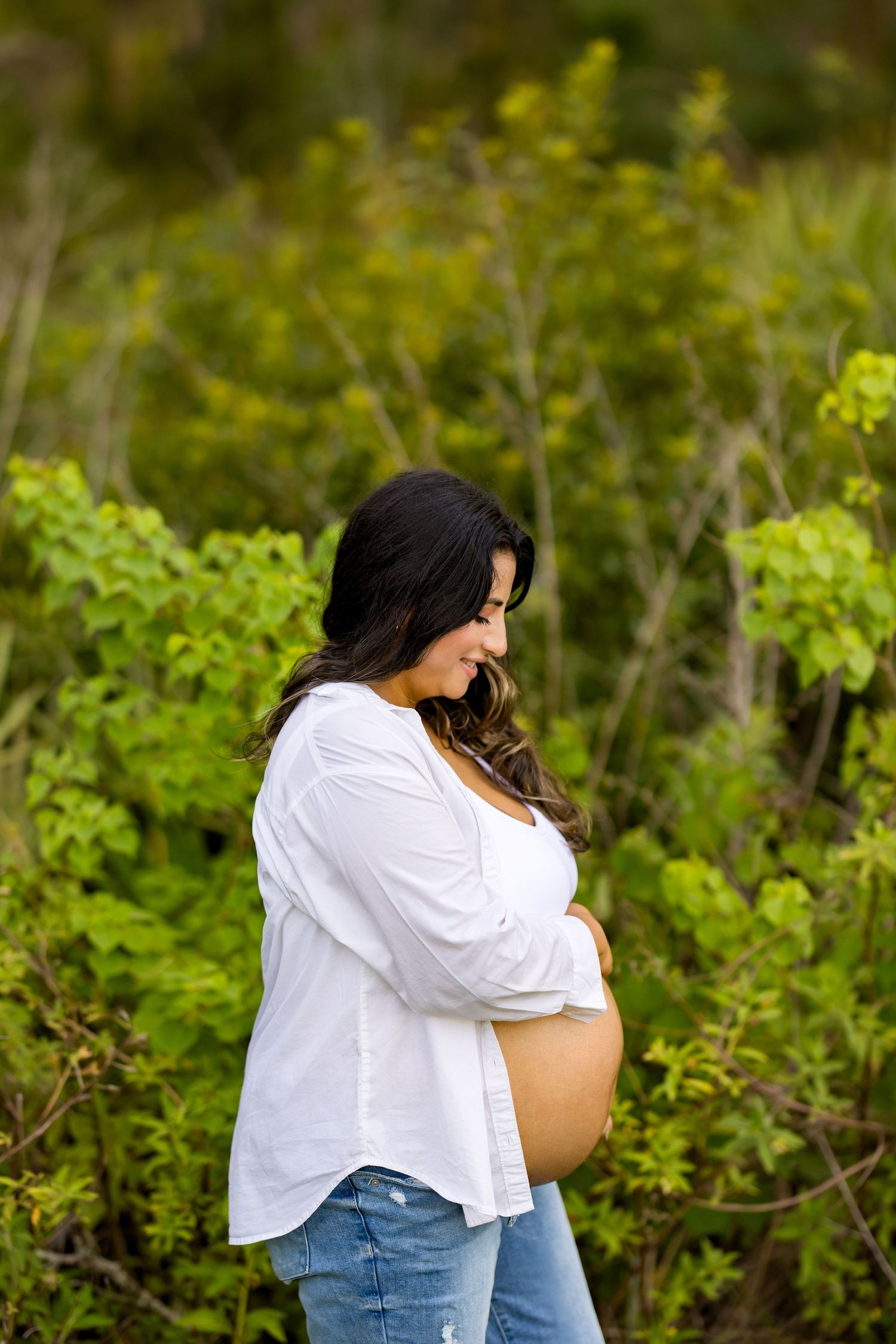 Loving maternity photos taken in lush garden setting with natural lighting.