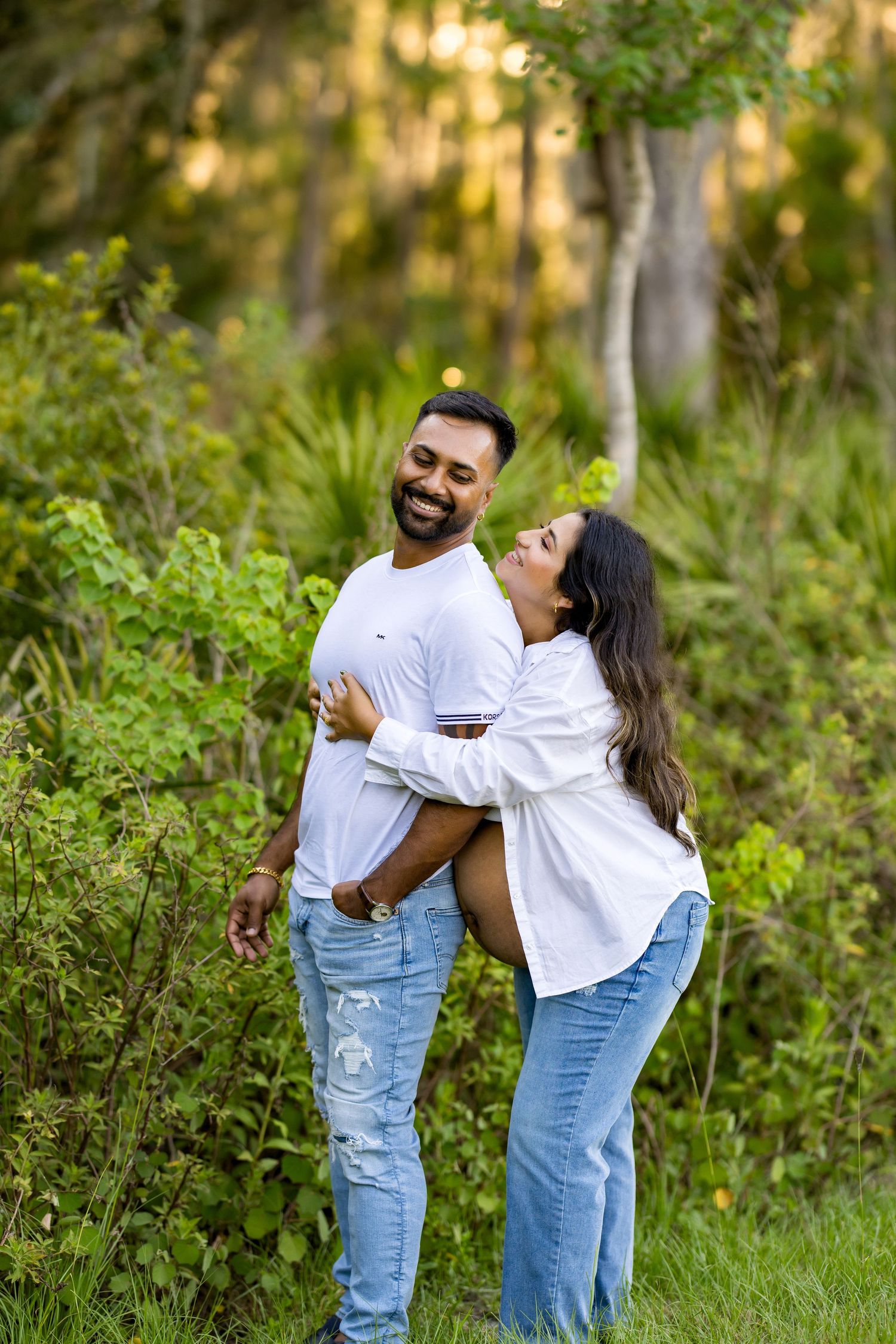 Playful maternity photos captured in outdoor garden setting during golden hour.