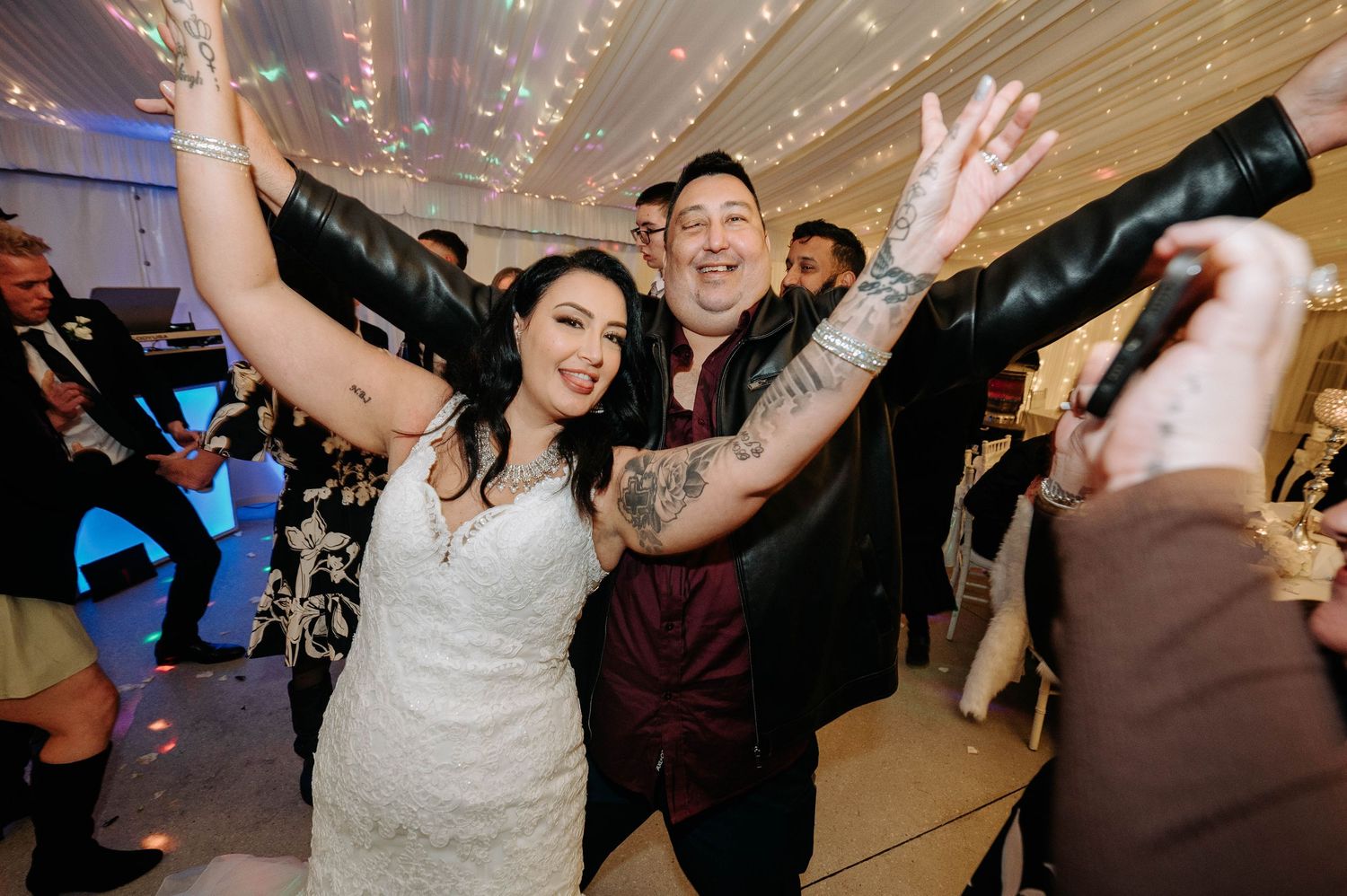 Dancing couple celebrates at wedding reception with festive disco lights and sparkles in elegant ballroom.