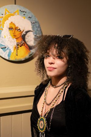 Art exhibit showing decorative circular painting of sun and moon themes on warm-toned wall.