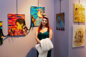 Art gallery exhibition showing colorful portrait paintings with viewer in foreground.