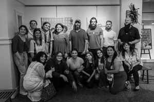 A black and white group photo of people gathered together in a casual indoor setting.