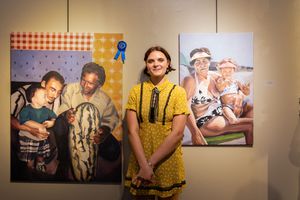 A gallery exhibition showing photographs on the wall with a person standing in front of them.