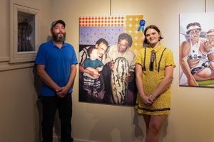 Two people standing in art gallery next to photographic exhibition display.