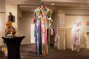 Colorful ceremonial robes and garments on display in a museum exhibit hallway with ambient lighting.