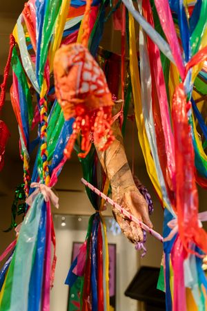 Colorful rainbow ribbons and decorative elements hang from above in an art installation display.