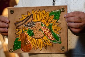 Leather bookmark featuring a hand-tooled sunflower design with green leaves against a natural tan background.