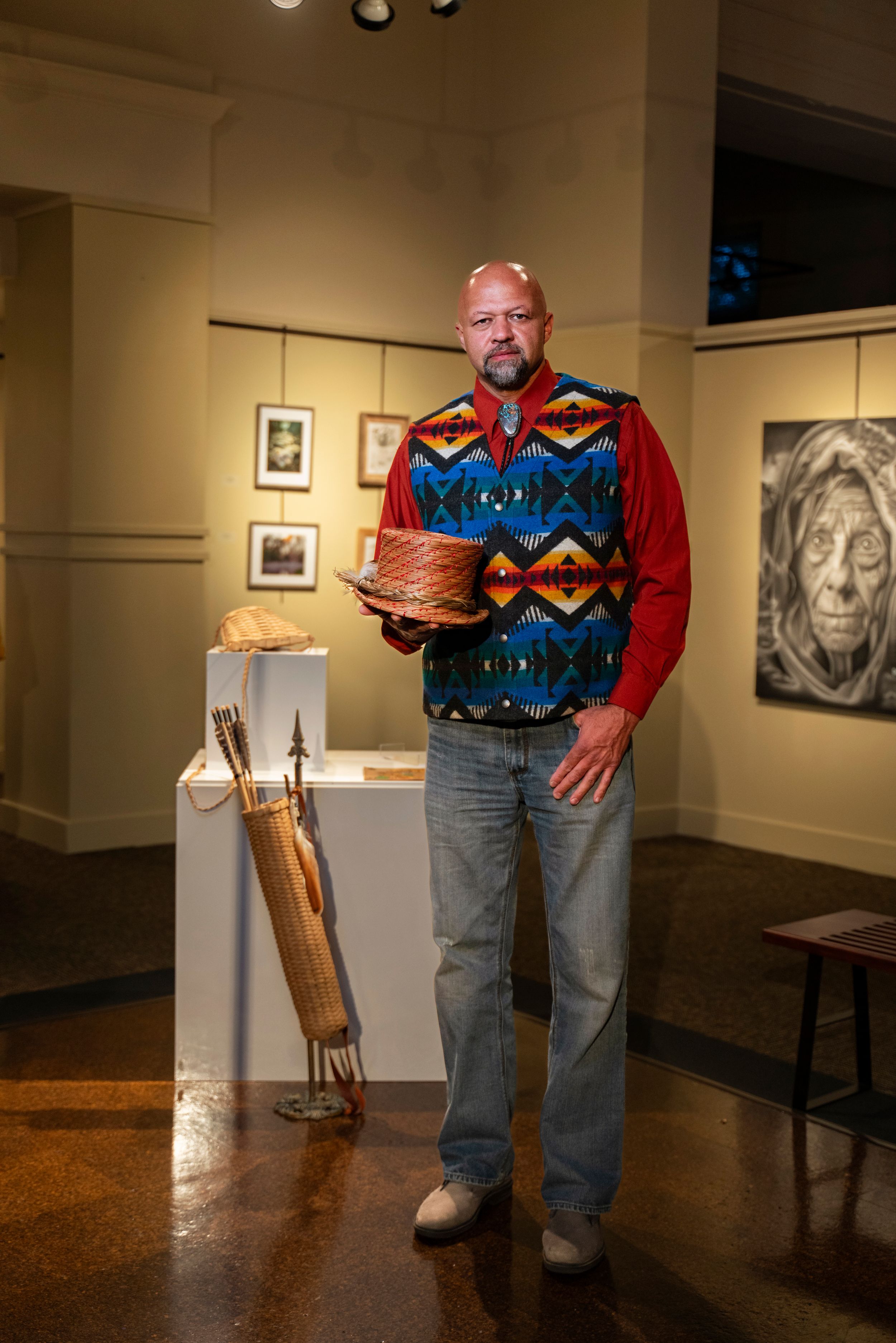 A gallery exhibition featuring southwestern art with a person wearing a colorful patterned sweater.