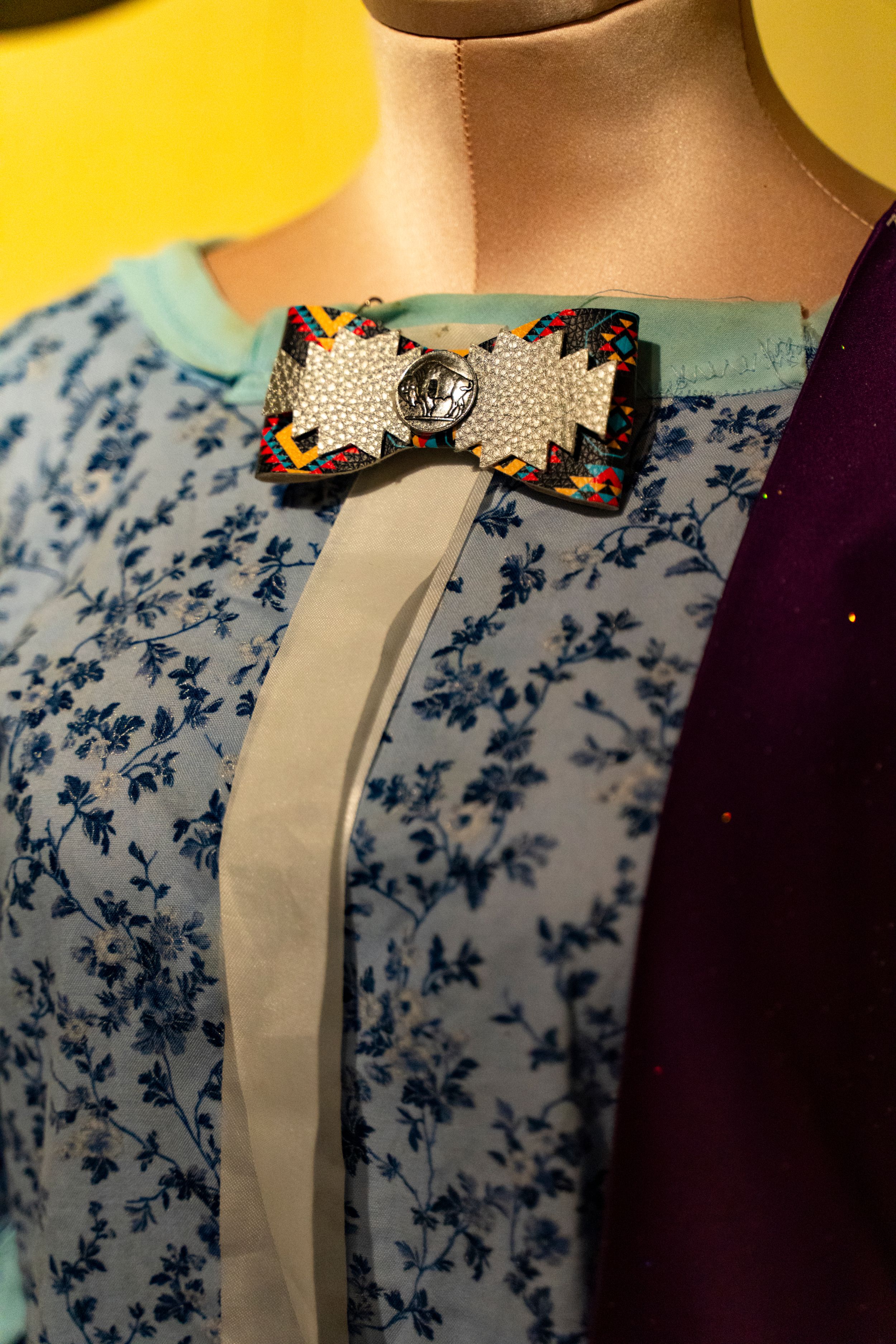Close-up of ornate beaded bow brooch on blue floral fabric.