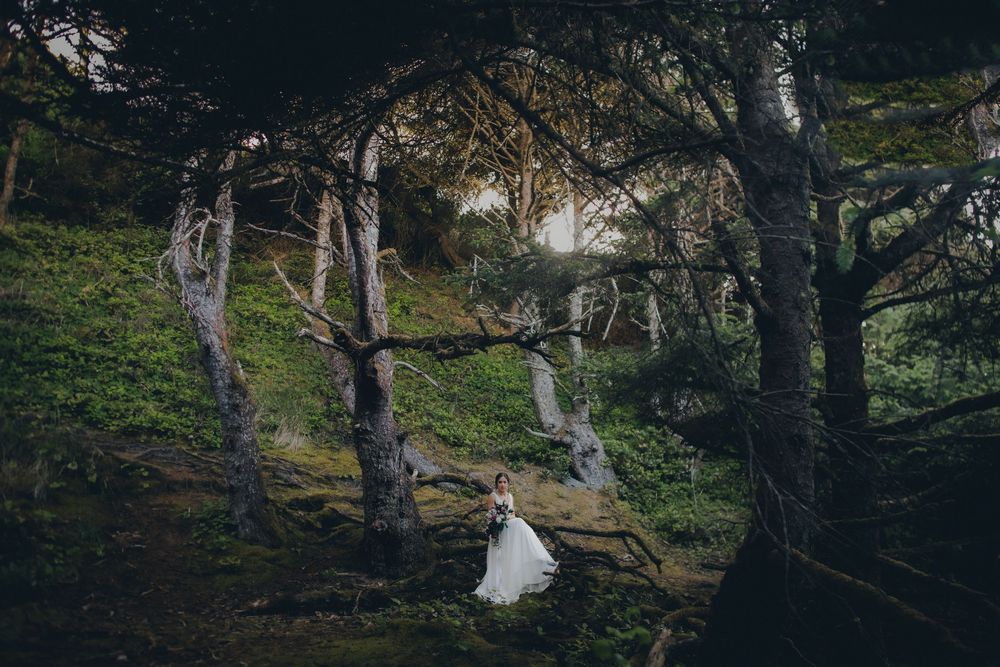 A white dress flows ethereally among mossy forest trees in a mystical woodland scene at sunset.