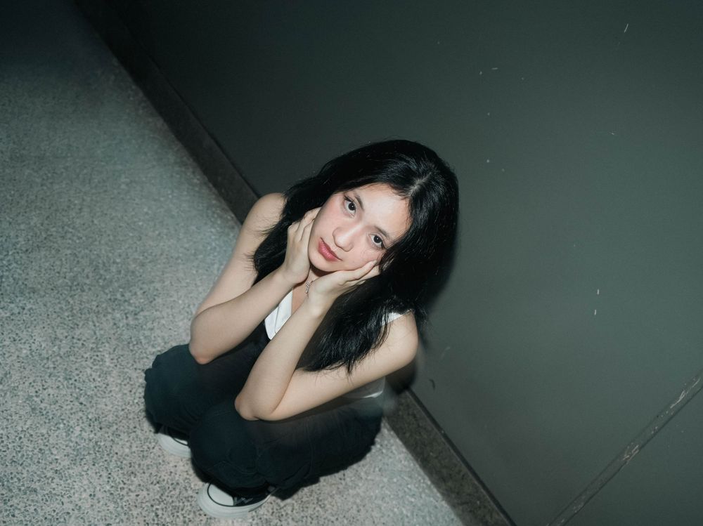 A dramatic black and white photograph of a person posing on the floor in low-key lighting.
