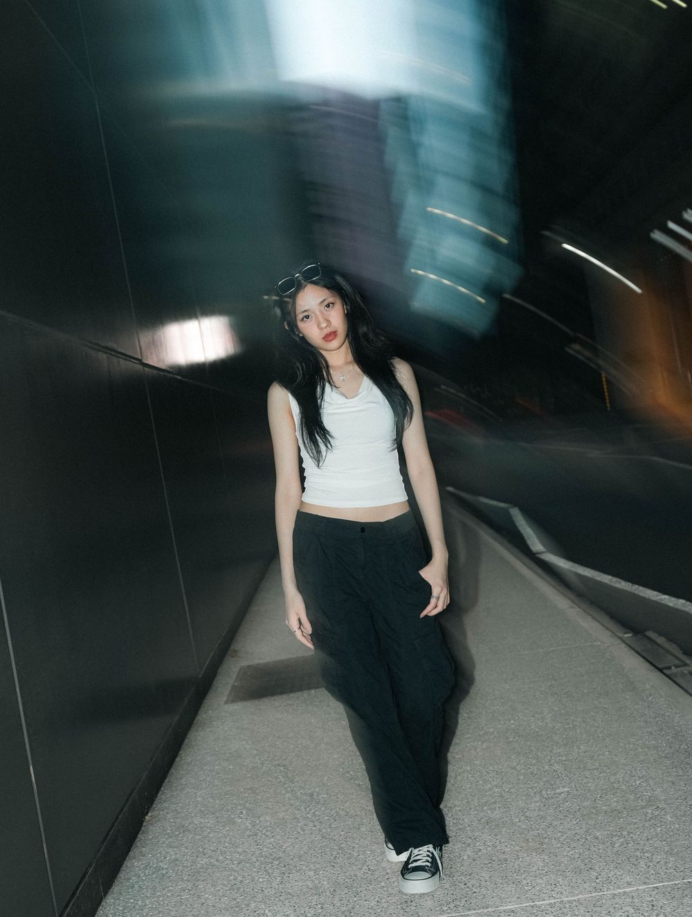 A figure in a white crop top and black pants poses in a tunnel with motion blur effects and dramatic lighting.