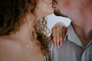Close up romantic portrait showing curly hair and hands touching in warm light.