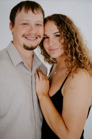 Happy couple portrait showing natural smiles and curly hair against white background.